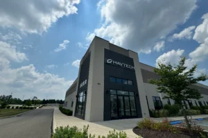Modern commercial building with "HAVTECH" signage on the facade, surrounded by landscaping under a partly cloudy sky.