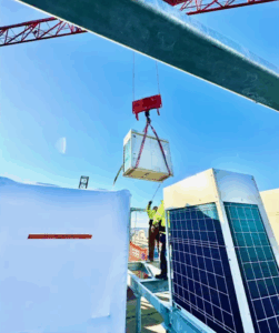 HVAC technician guides a Daikin VRV unit being lifted by crane onto a rooftop during the Cotton Annex retrofit in Washington D.C.
